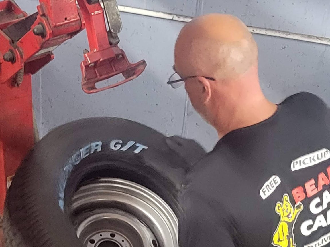 Bear Car Care technician mounting a tire on a steel wheel at the tire changer